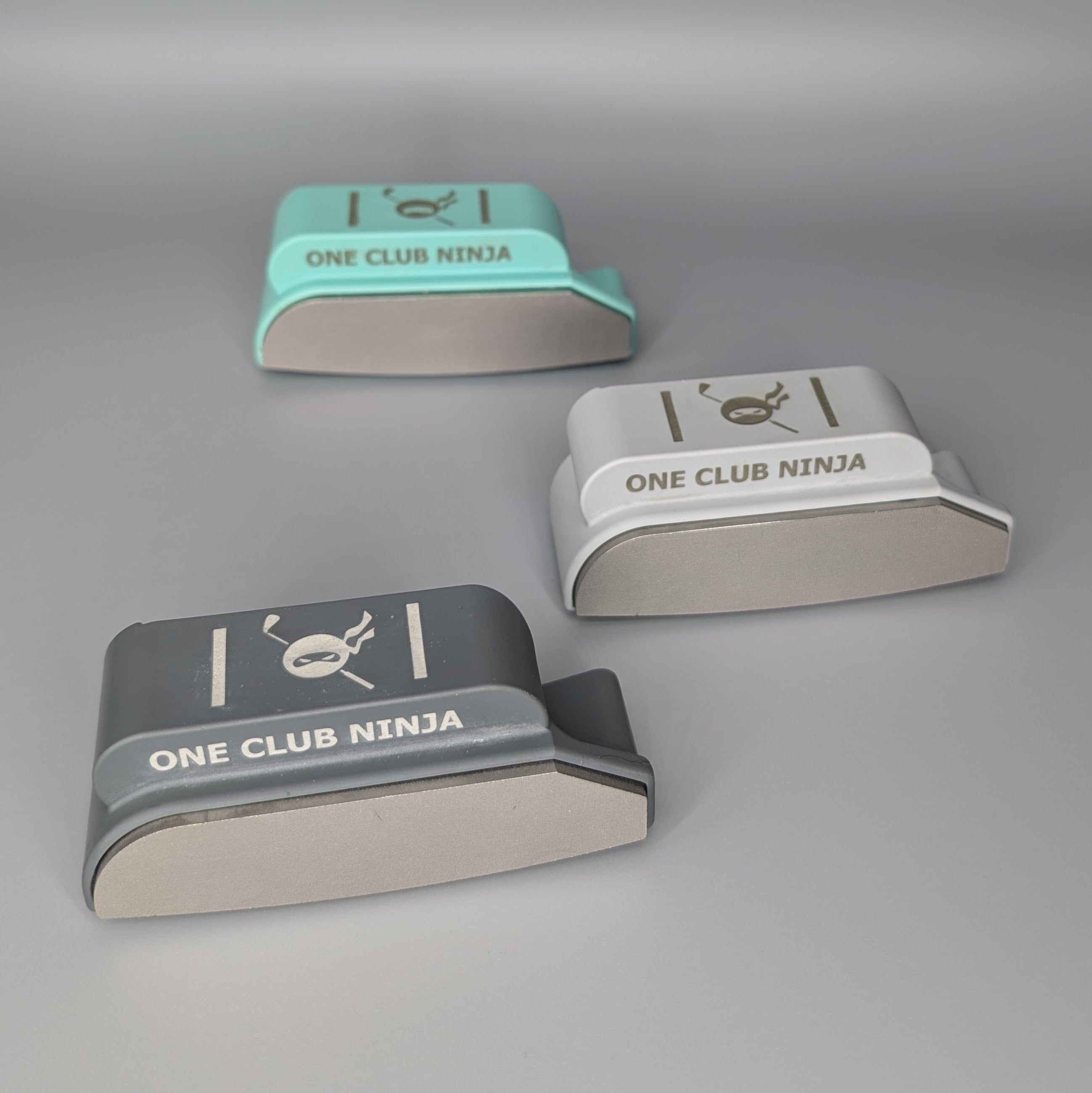 Three One Club Ninja putter attachment colors arranged together on a gray background
