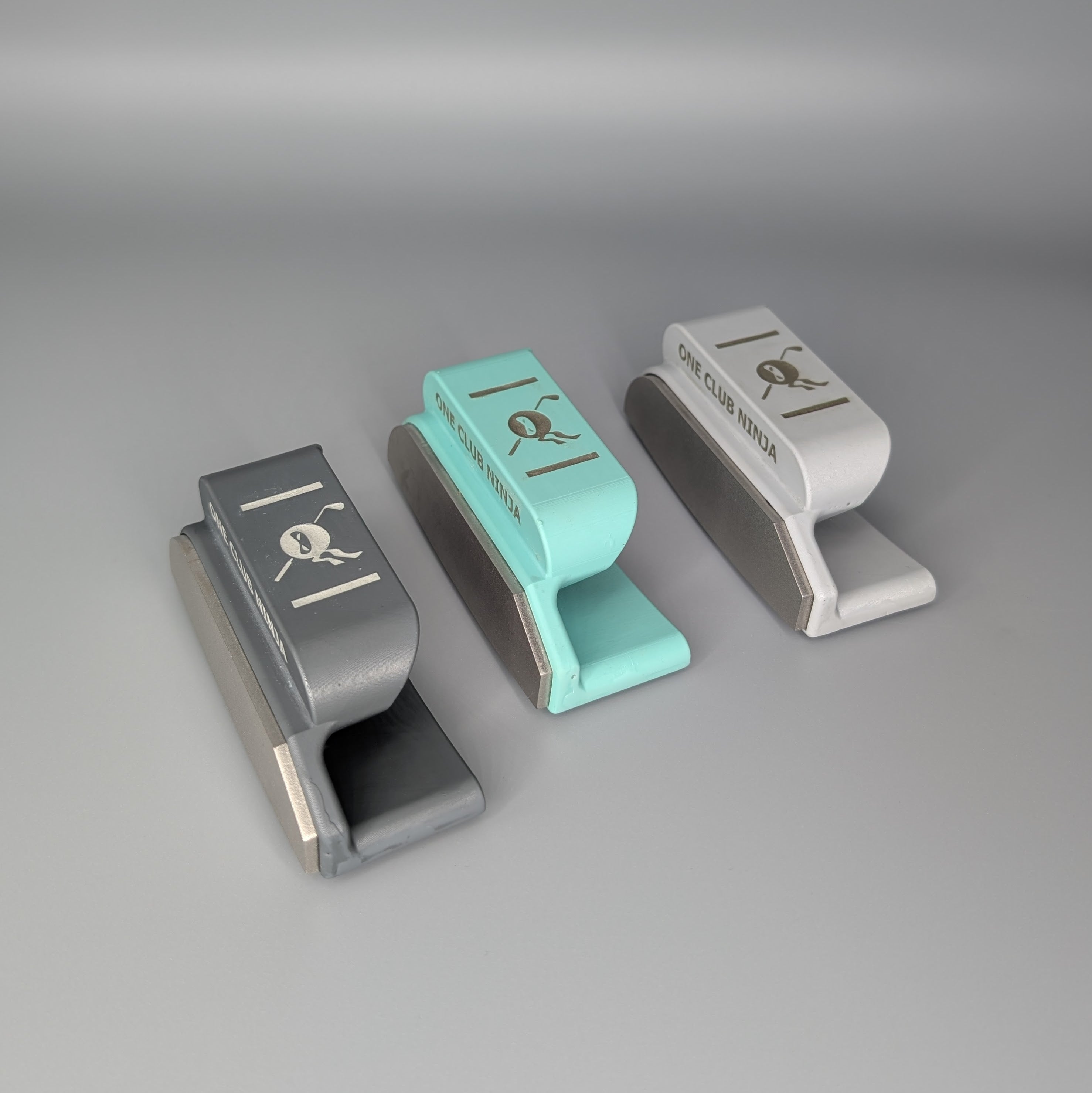 Three One Club Ninja putter attachments lined up in Obsidian, Green, and Light Gray